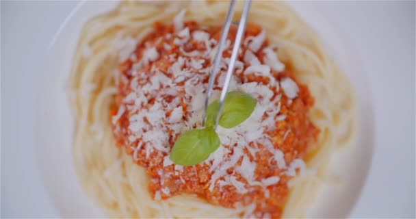 Primer plano de pinzas que adornan la albahaca en espaguetis — Vídeo de stock