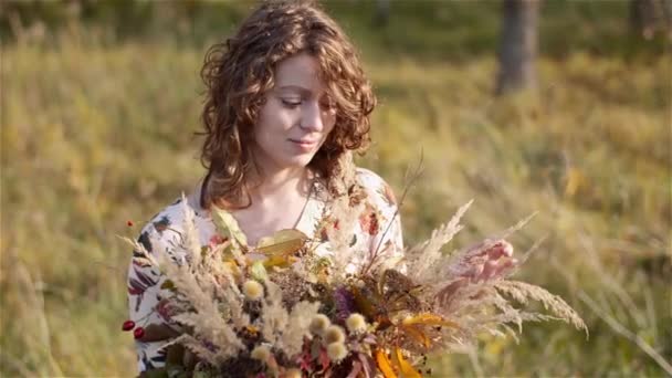Портрет жінки, що дивиться на букет з диких квітів влітку . — стокове відео