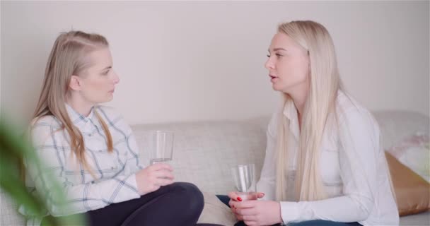 Deux femmes qui boivent de l'eau dans le salon parlent et sourient. — Video