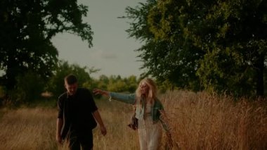 Affectionate Hipsters Walking and Smiling in Summer at Sunset