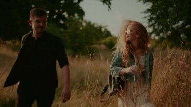 Affectionate Hipsters Walking and Smiling in Summer at Sunset