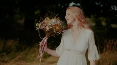 Kaygısız Boho Kadını yazın çayırda yürüyor ve gülümsüyor.