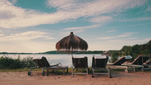 Lounge chairs and sunshades at lakeshore — Stock Video