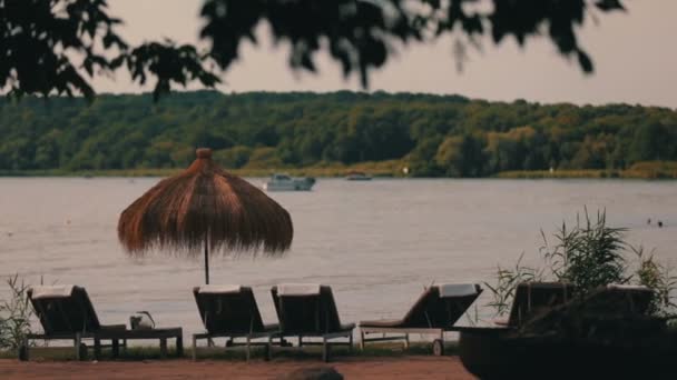 Cadeiras de estar e guarda-sóis na margem do lago — Vídeo de Stock
