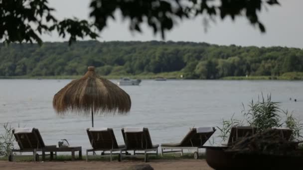 Sillas de salón y sombrillas a orillas del lago — Vídeo de stock