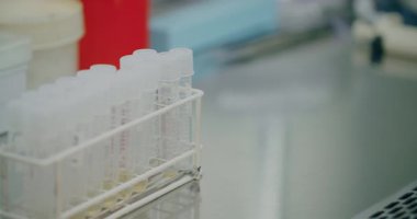 A scientist carefully extracts a test tube from a rack and mixes the antidote solution inside.