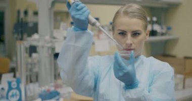 Female scientist pipetting genetic material on Petri dish in a research center.