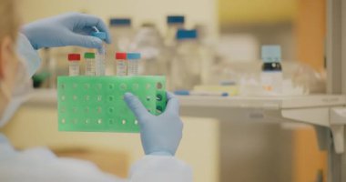 A laboratory worker inserts small test tubes into a device that shakes and mixes them using a special vibration technique.