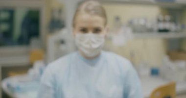 Portrait of a female scientist wearing a protective mask in a modern medical lab background.