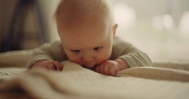 Adorable close-up of a tiny baby holding a blanket while beginning to crawl for the first time, showcasing early developmental stages.