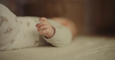 A close-up view of a tiny, delicate newborns hand resting softly against a textured blanket.