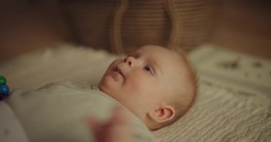 Cute baby boy lying on a blanket holding a wooden toy, capturing a heartwarming infant moment.