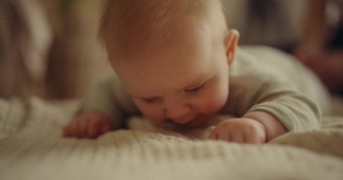 Adorable baby lying on its stomach on a cozy blanket, yawning during a sweet moment. Perfect for parenting or family themes.