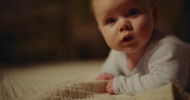 A close-up portrait of a newborn baby boy with a smiling face. Strong focus on the babys expression and features.