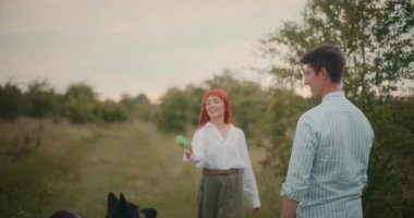 Mutlu çift, Alman çoban köpekleri ile oynuyor. Neşeli bir açık havada sevgi ve arkadaşlık sergiliyorlar..