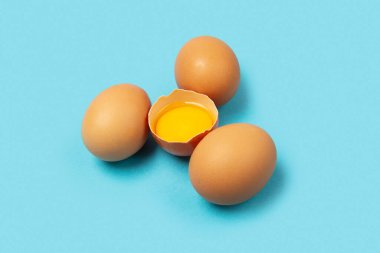 Mavi arka planda dört tavuk yumurtası.