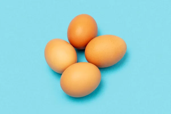 Mavi arka planda dört tavuk yumurtası.