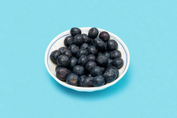 Mavi arka planda bir tabakta yaban mersini