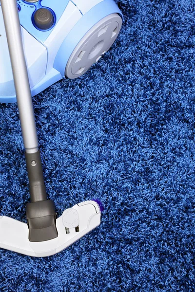 The metal pipe of vacuum cleaner in action -clean a carpet and laminated flooring board.