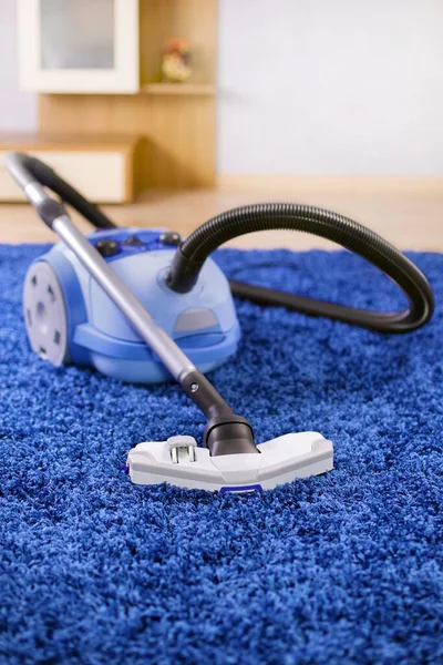 Powerful vacuum cleaner stand  on blue carpet.
