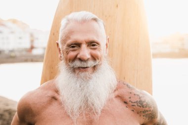 Yaz günbatımında plajda elinde klasik tahta sörf tahtası tutan mutlu sörfçü - eğlence ve spor kavramı - yüze odaklan