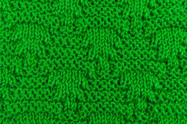 Arka plan olarak yünlü şeylerin örülmüş yüzeyi. Yumuşak kumaş yeşil renkli örgü desenli dokunun yakın çekimi. Sıcak kış giysileri. Metin için kopya alanı olan arkaplan tekstil yüzeyi.