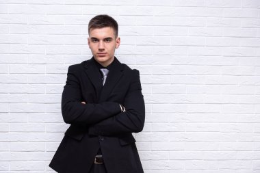 Beyaz tuğla duvarın arkasında duran yakışıklı, kendine güvenen iş adamı.