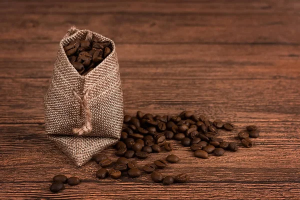 a cup of coffee and coffee beans in a bag on a dark background, top view