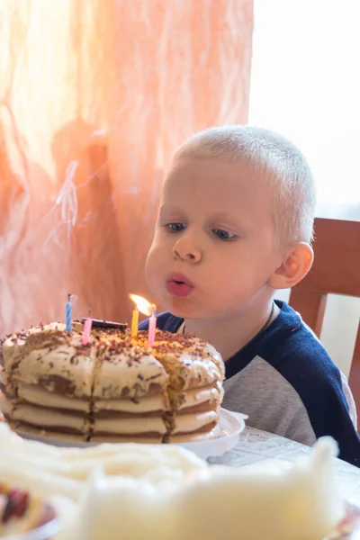 Pojken blåser ut ljusen på tårtan — Stockfoto