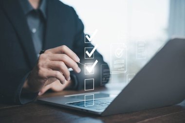 İş kontrol listesi ve belge doğrulama kavramı. Bir iş adamı sanal ekranda bilgisayardaki görevleri kontrol etmek için Stylus 'u kullanıyor. Dijital görev yönetimi, iş akışı süreci ve çevrimiçi form onay sistemi.