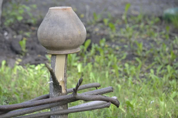 Krynka starą ceramiczną w ogrodzenia wiklinowe z gałęzi na zielonym tle — Zdjęcie stockowe