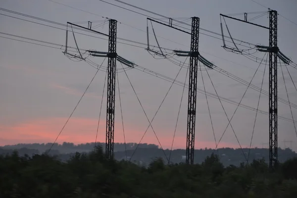 3 つの柱とピンクの太陽の背景に電力線を呼び出す — ストック写真