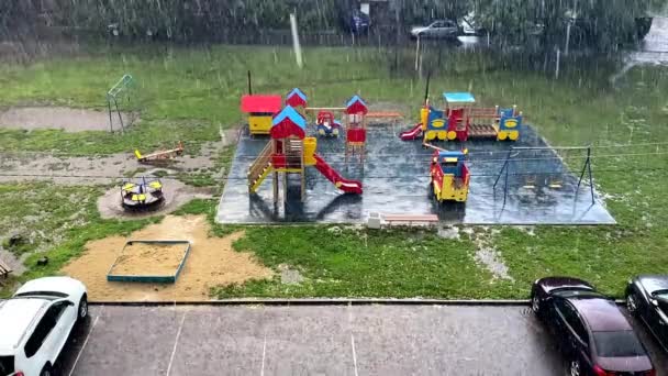 Παιδιά οδηγούν μια κούνια στη βροχή στην παιδική χαρά σε ένα βίντεο διακοπών καλοκαιρινής ημέρας — Αρχείο Βίντεο