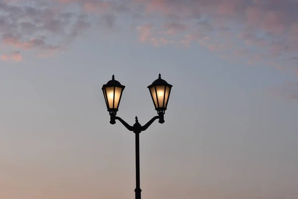 street lamp with lamps on against a background of dark clouds at dusk. embankment of the Gulf of Finland Strelnya Russia