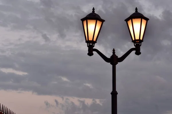 Alacakaranlıkta Karanlık Bulutların Arka Planında Lambaları Açık Olan Sokak Lambası — Stok fotoğraf