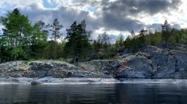 Ladoga skerries. Karelia Rusya 'nın güzel doğası. Kayalık kıyılar yosun ve taşların üzerindeki çam ağaçları ile kaplıdır. Sakin göl suyu dalgaları. Küçük dalgalar. gök gürültülü bulutlar
