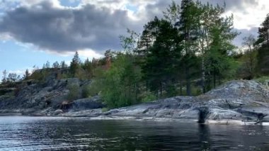 Ladoga skerries. Karelia Rusya 'nın güzel doğası. Kayalık kıyılar yosun ve taşların üzerindeki çam ağaçları ile kaplıdır. Sakin göl suyu dalgaları. Küçük dalgalar. gök gürültülü bulutlar