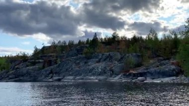 Ladoga skerries. Karelia Rusya 'nın güzel doğası. Kayalık kıyılar yosun ve taşların üzerindeki çam ağaçları ile kaplıdır. Sakin göl suyu dalgaları. Küçük dalgalar. gök gürültülü bulutlar