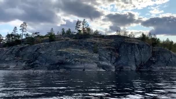 Ladoga skerries. krásná povaha Karelie Rusko. Kolem se vznášejí skalnaté břehy pokryté mechem a borovicemi na kamenech. Vlnky klidné vody z jezera. Malé vlny. bouřkové mraky — Stock video