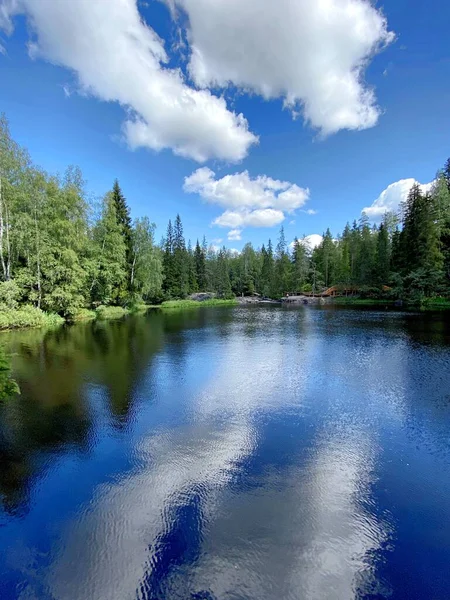 雲のある青空は緑の木々を背景に湖の貯水池に映し出されます ロシアの北の美しい風景 カレリア Akhvenkoski滝公園 — ストック写真