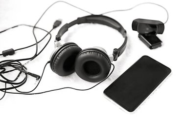 Kulaklıklar telefon web kamerası beyaz bir battaniye üzerinde siyah beyaz fotoğrafçılık