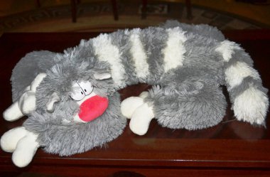 yumuşak oyuncak çizgili gri ve beyaz kedi masanın üzerinde yatan