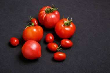 Siyah arka planda sulu domatesler, çiftlik sebzeleri.