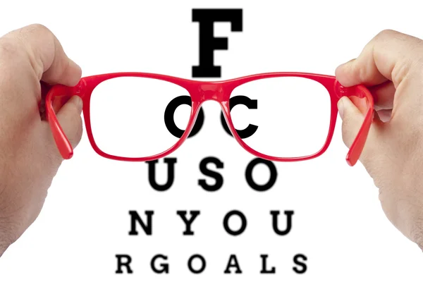Red spectacles focusing on text focus on your goals arranged as eye chart test — Stock Photo, Image
