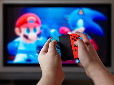 Erkek oyuncu elleri konsol kontrolünde büyük ekranda ya da TV 'de video oyunu oynuyor. Oyun denetleyicisinin bakış açısı veya pov ekranın önünde oynarken