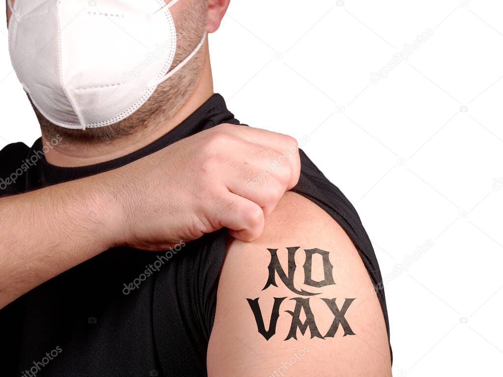 Man wearing protective mask protests against new covid-19 vaccine showing tattoo no vax on his arm. Anti vax person rejecting syringe with anti covid vaccine. Freedom of choice about own health