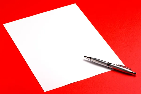 Folha de papel em branco com caneta no fundo vermelho — Fotografia de Stock