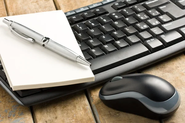 Computer keyboard mouse and pen on notebook on rustic wooden table — Stock Photo, Image