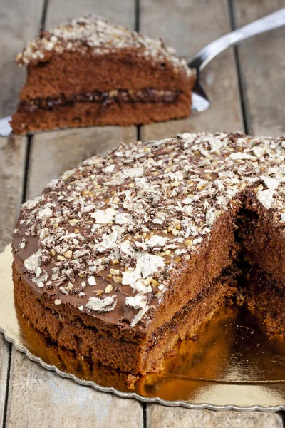 Нарезанный кусочек шоколадного десерта на ломтик серебряного торта на деревянном деревенском столе — стоковое фото