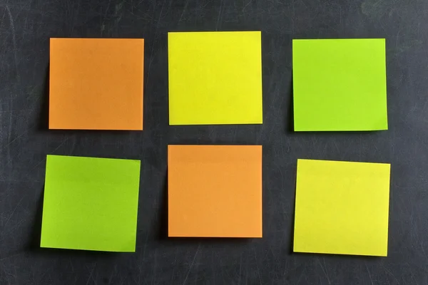 Κενό πράσινο πορτοκαλί και κίτρινο postits κόντρα στον πίνακα ή chalkboard — Φωτογραφία Αρχείου